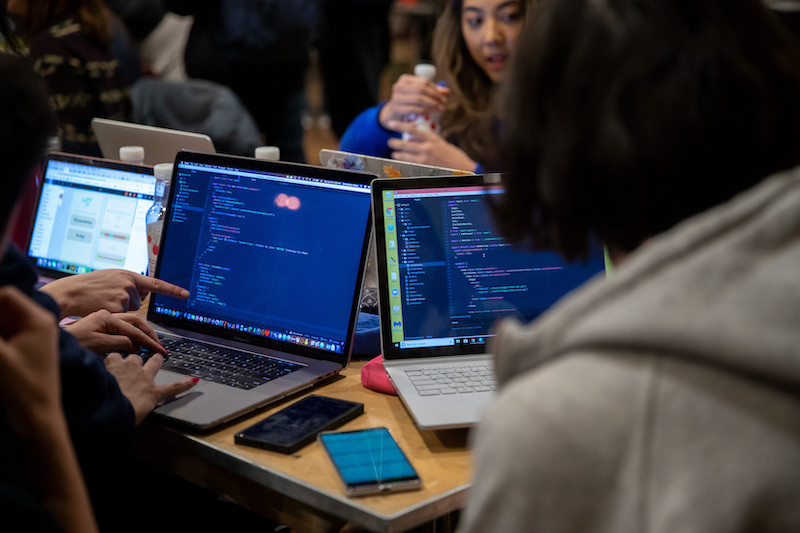 Students look over code on a laptop during Hack@Brown.